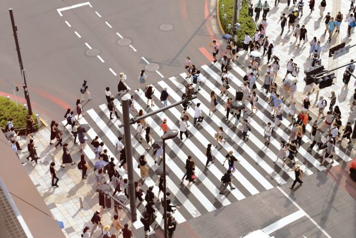 A crowd of people crossing a street in multiple directions
